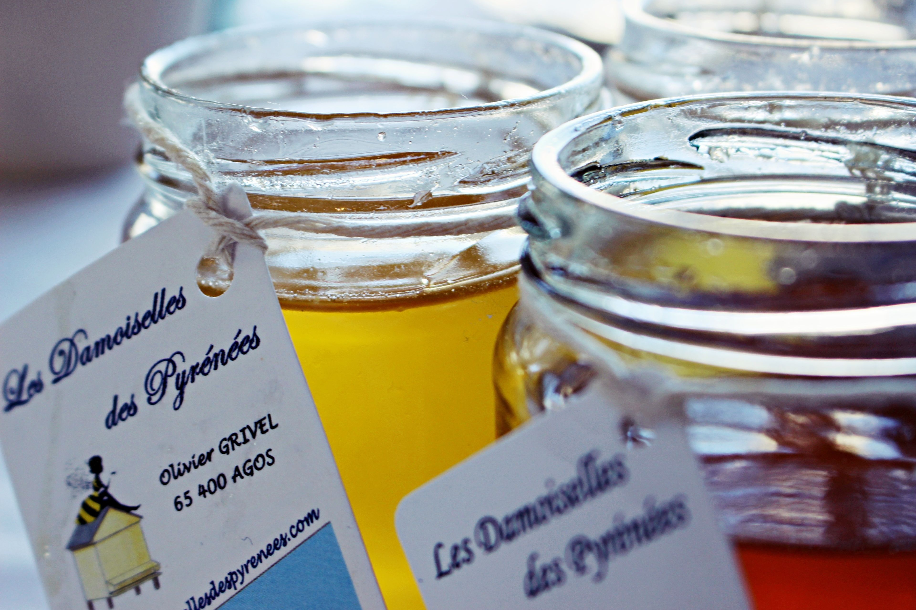A close-up of glass jars with labels, likely containing food items, and a tag with text and a small illustration.