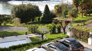 A parking area with several luxury cars, a river, and a town in the background. - Belfry Spa by Ligne St Barth (Lourdes)