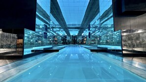 A modern, spacious lobby with a reflective floor and glass walls, featuring a central open space and symmetrical design. - Belfry Spa by Ligne St Barth (Lourdes)