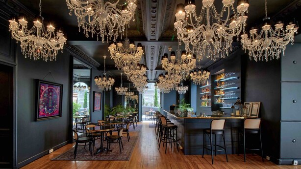 A bar area with multiple chandeliers, wooden flooring, and bar stools. - Belfry Spa by Ligne St Barth (Lourdes)