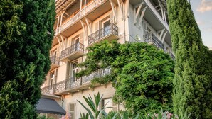 A multi-story building with balconies, surrounded by lush greenery and tall trees. - Belfry Spa by Ligne St Barth (Lourdes)