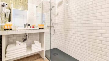 A modern bathroom with white subway tiles, a glass-enclosed shower, and a vanity with toiletries.