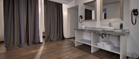 A modern bathroom with a large mirror, a sink, and a shower area.