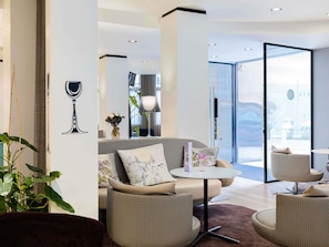 A modern living room with a sofa, armchairs, a coffee table, and a glass door leading outside. - Mercure Nice Centre Grimaldi (Nice)