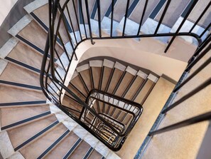 A spiral staircase with a black metal railing, beige steps, and marble accents. - Mercure Nice Centre Grimaldi (Nice)
