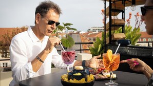 Un hombre y una mujer cenando al aire libre en una mesa con diversos alimentos y bebidas.