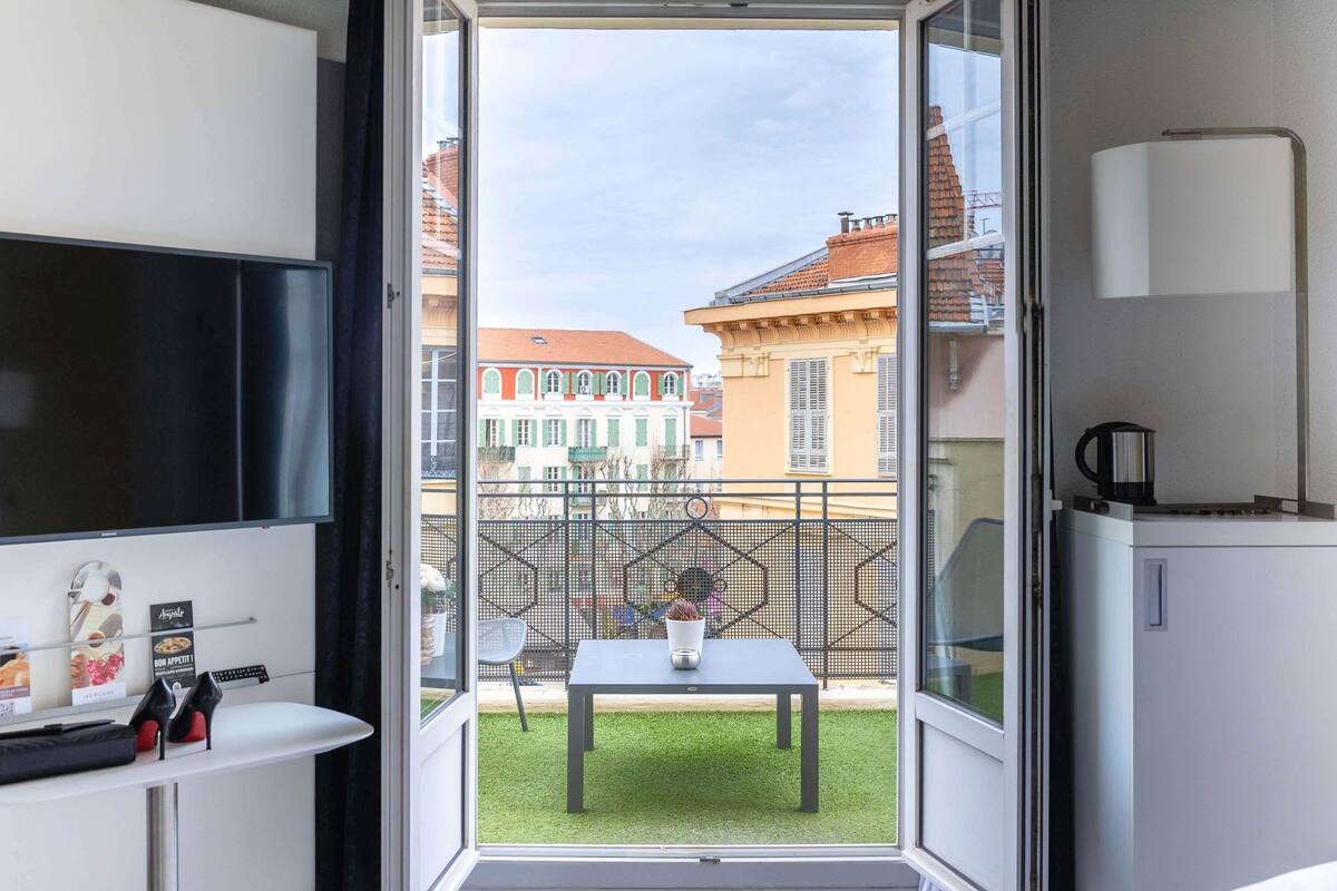 Ein Balkon mit Tisch, Stühlen, einem Fernseher und einer Kaffeemaschine.