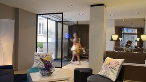 A modern hotel lobby with a reception desk, seating area, and a glass partition. - Mercure Nice Centre Grimaldi (Nice)