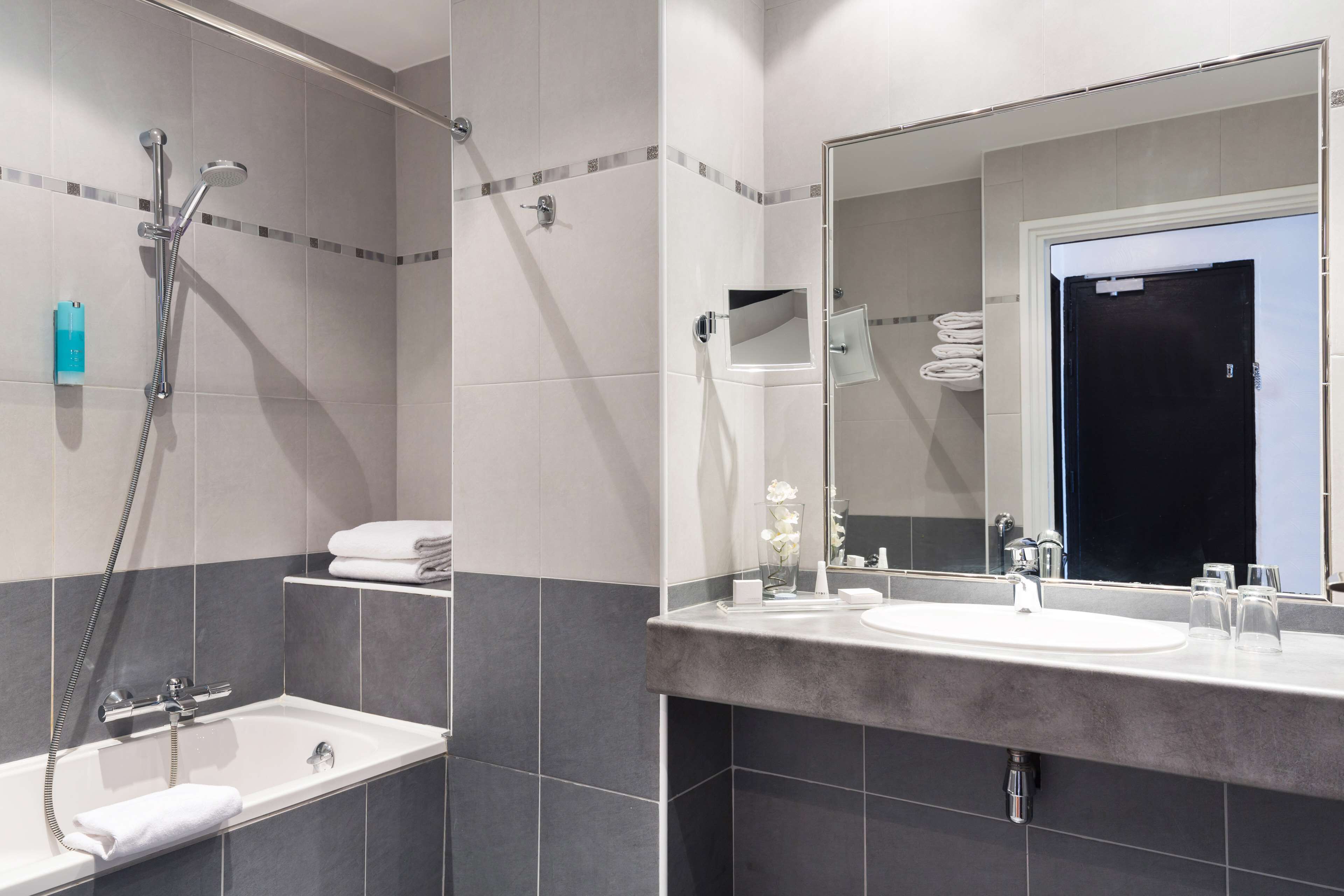 A modern bathroom with a bathtub, shower, and sink.