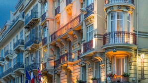 A historic building with ornate balconies, large windows, and a sign indicating it is a hotel.