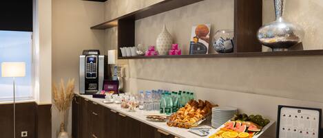 A breakfast buffet with various food items, beverages, and a coffee machine.