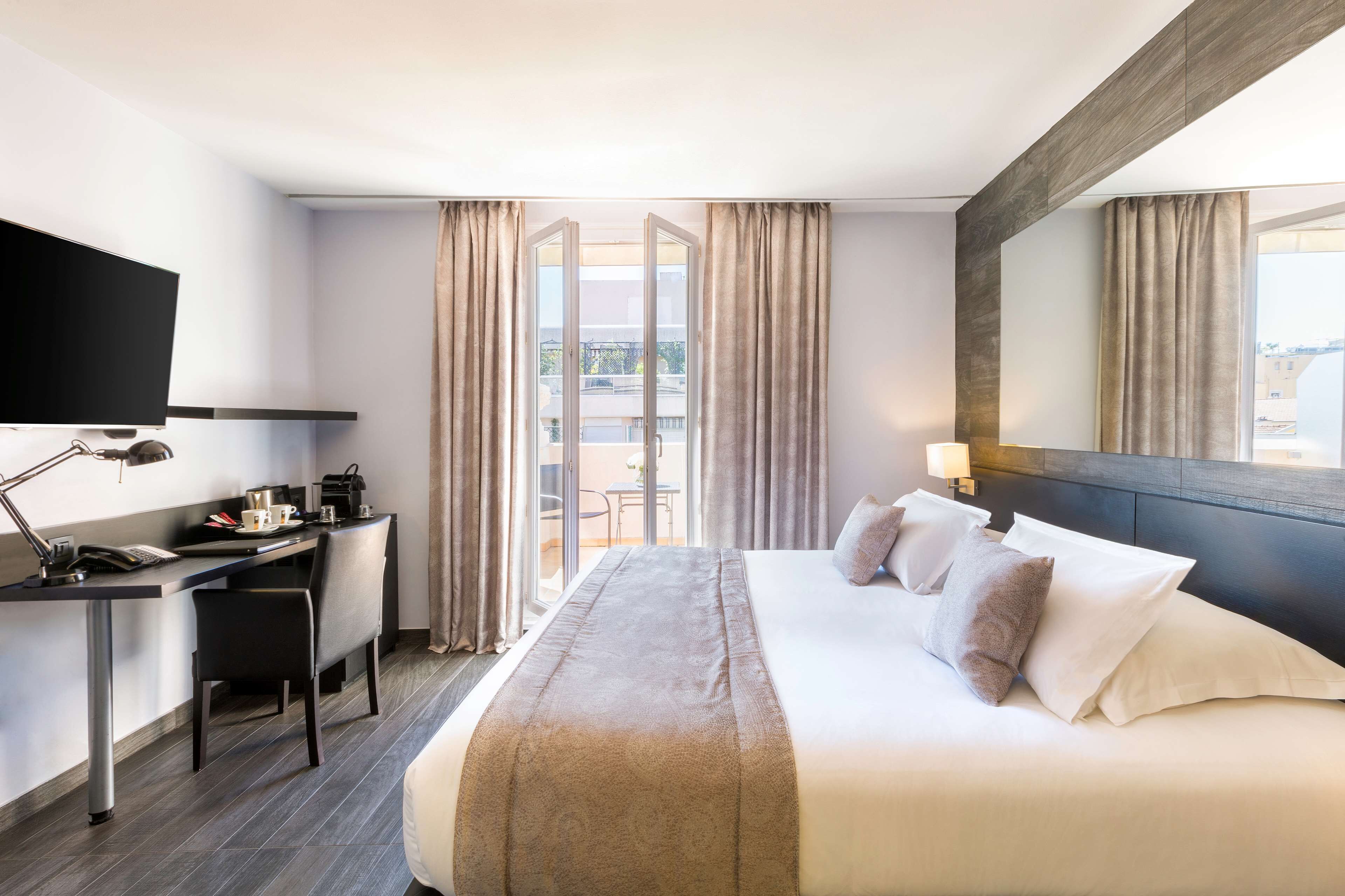 Una habitación de hotel con cama, escritorio, silla y televisor.