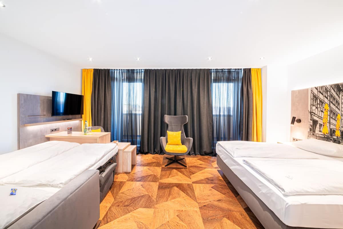 A hotel room with two beds, a TV, a desk, and a chair.