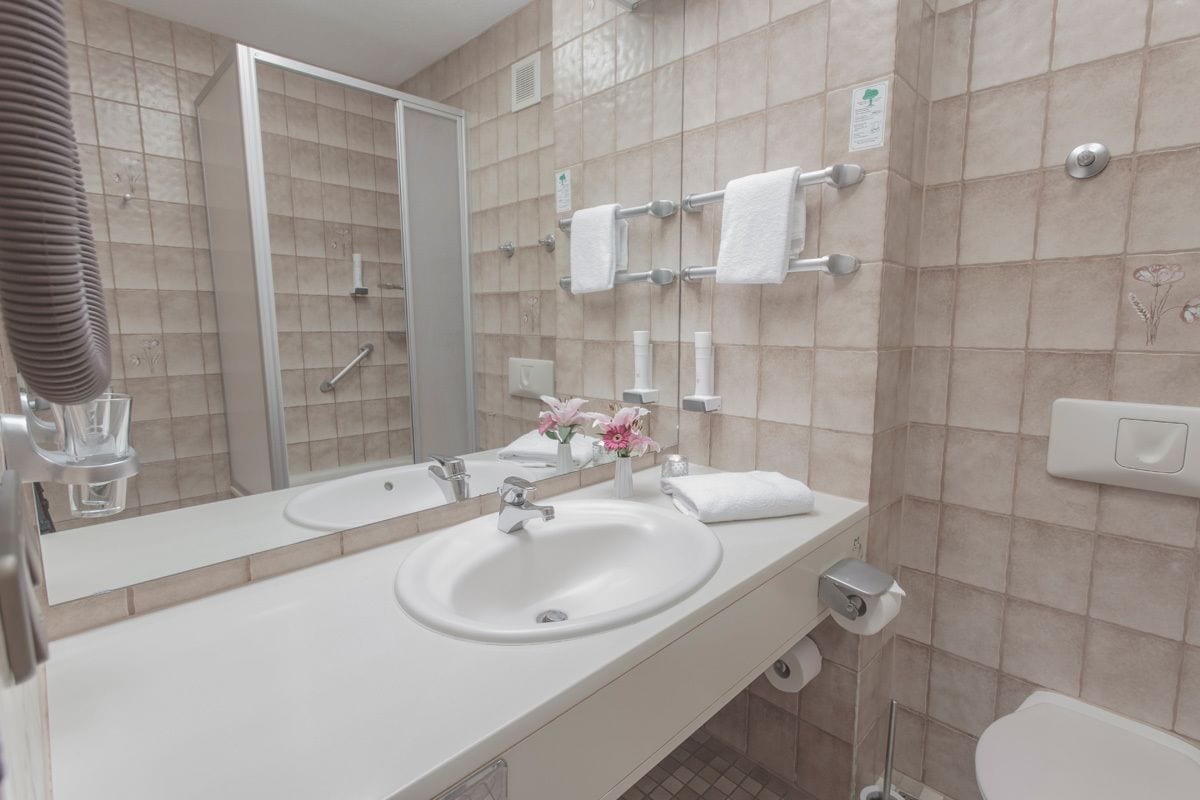 A modern bathroom with a white sink, mirror, and towel rack.