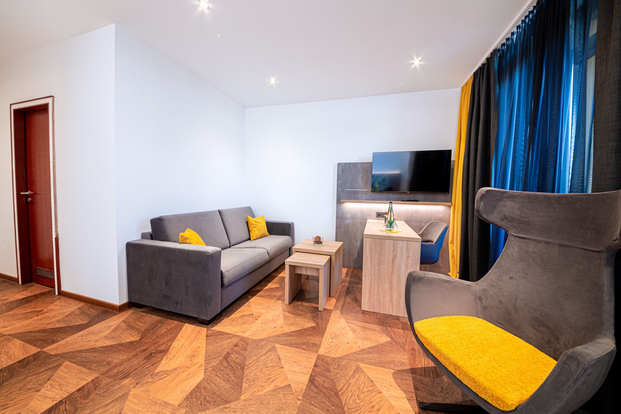 Una sala de estar moderna con un sofá, una mesita, una silla y un televisor.