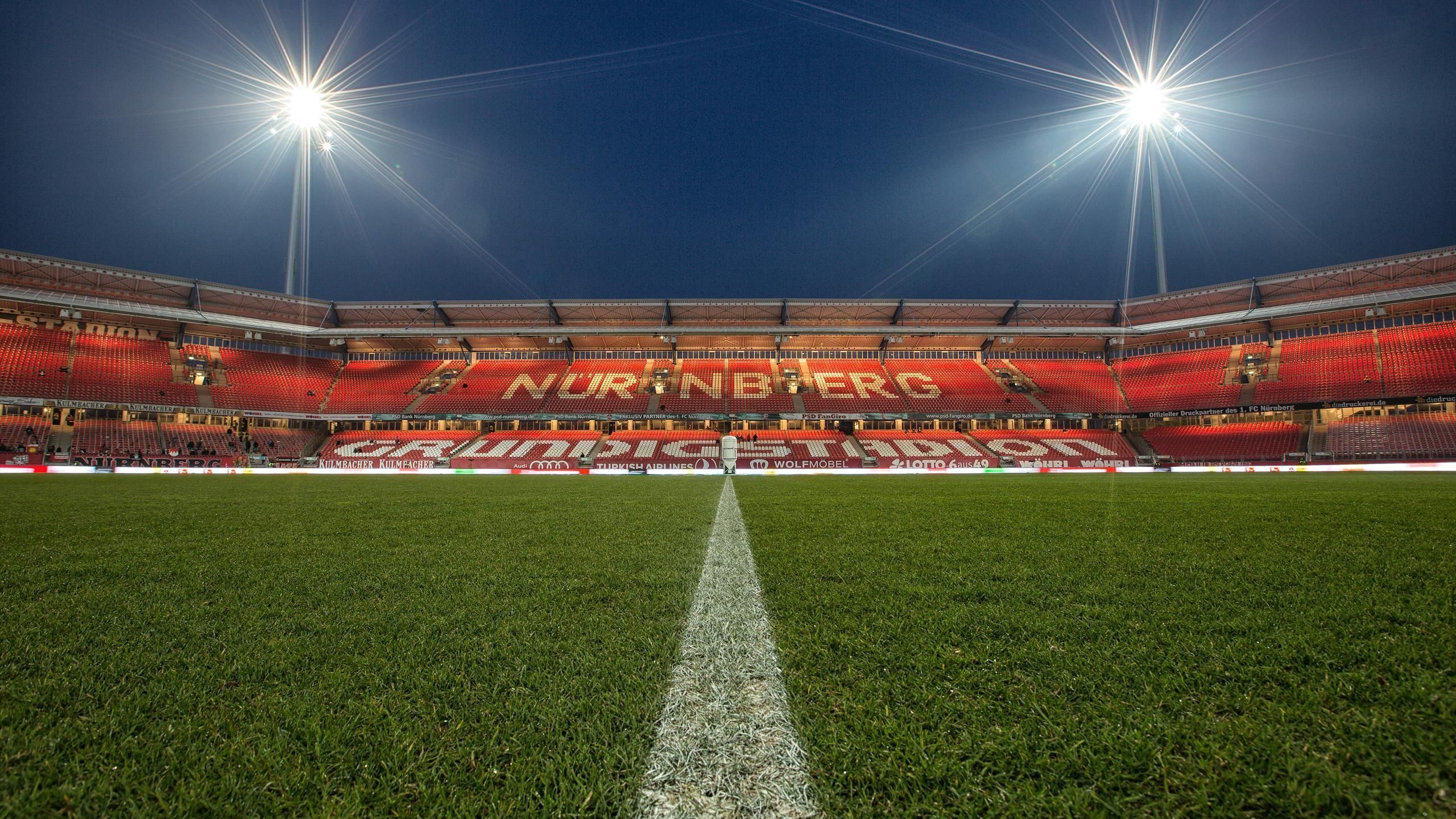 Un estadio con asientos rojos y un gran cartel.