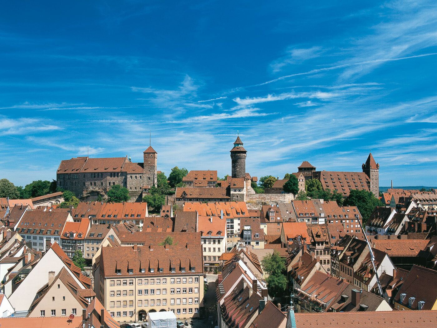 A historic town with medieval architecture, including a prominent castle with towers and a church with a tall steeple.