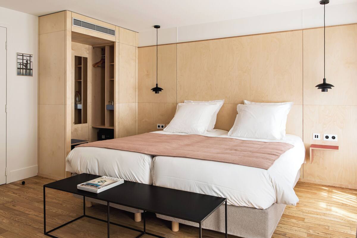 A modern bedroom with a large bed, a wooden wardrobe, and a small table.