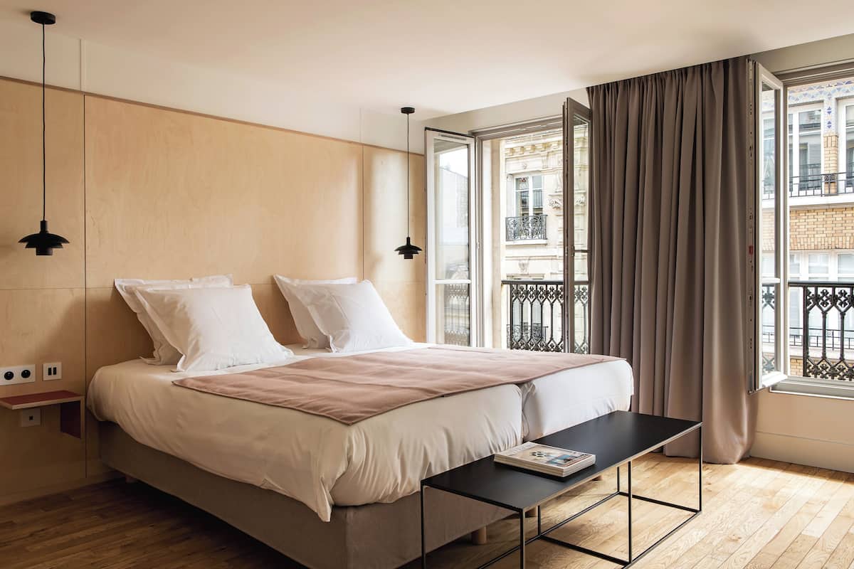 A modern bedroom with a bed, bedside tables, and a window with curtains.