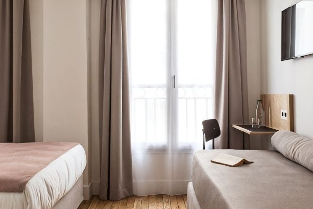 A hotel room with two beds, a desk, and a chair.