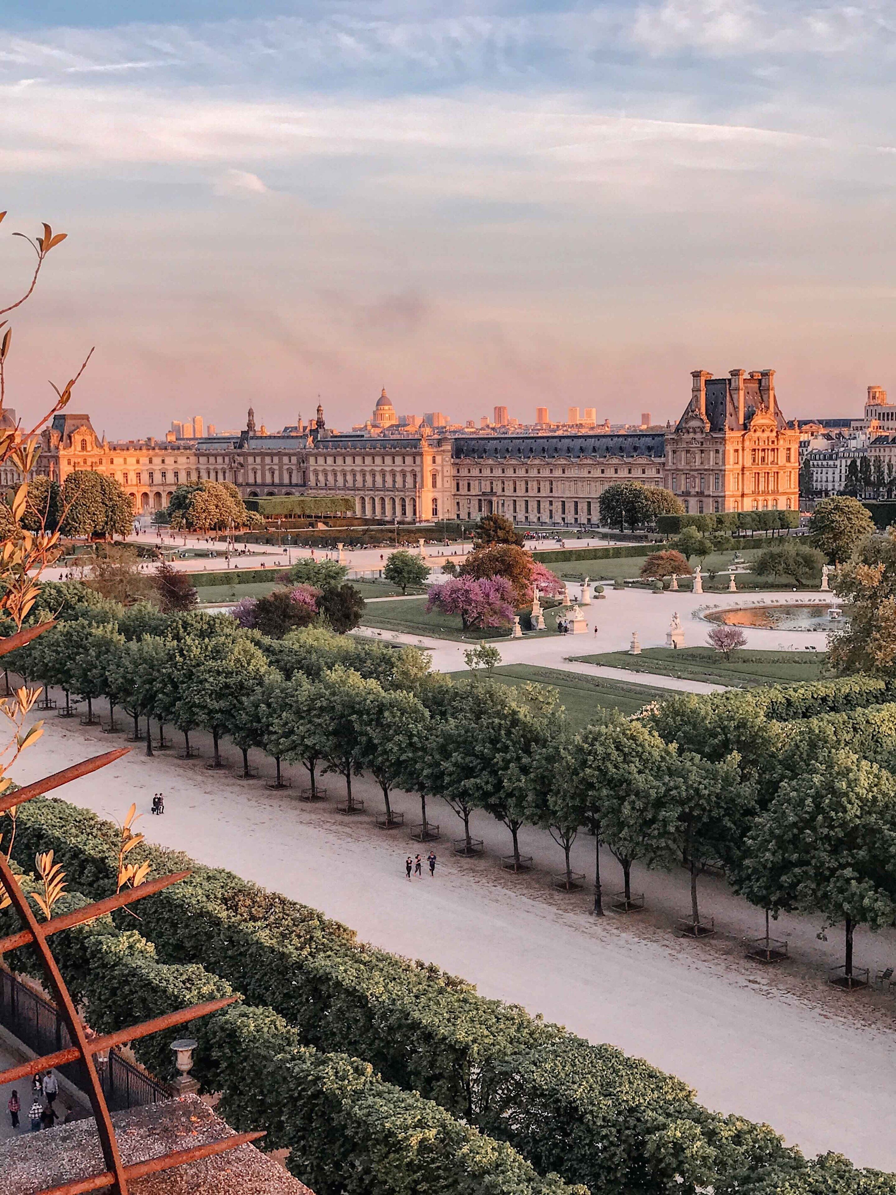 Vista del patio del Museo del Louvre con un edificio grande al fondo.