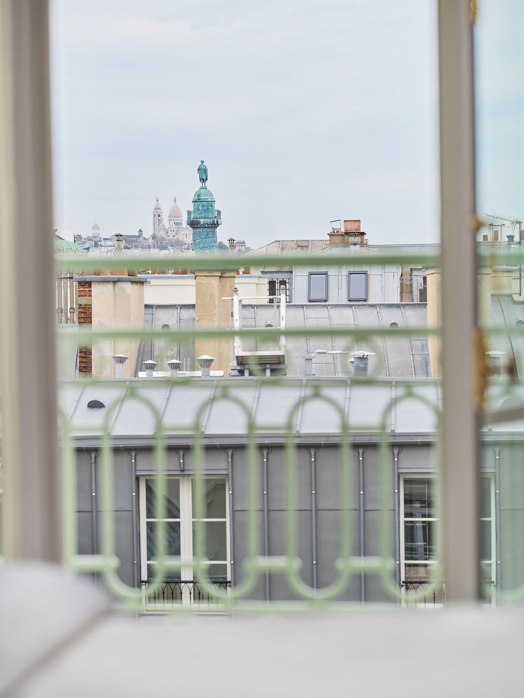 Vista de un paisaje urbano a través de una ventana con barandilla metálica.