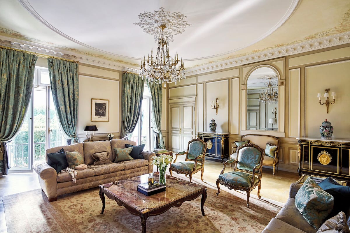 A spacious living room with a large sofa, two armchairs, a coffee table, and a chandelier.