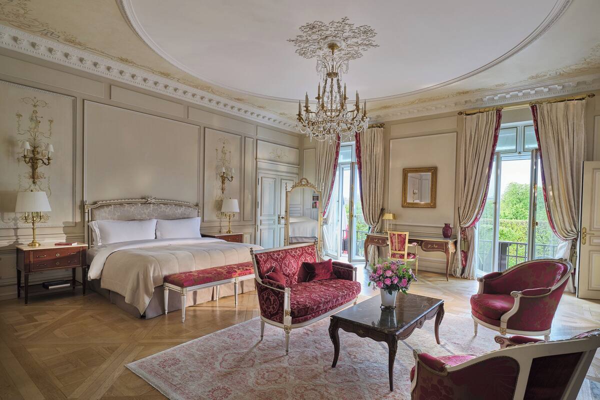 A luxurious bedroom with a large bed, ornate chandelier, and elegant furniture.