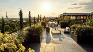 A rooftop terrace with outdoor seating, a view of the Eiffel Tower, and a garden area. - Le Meurice - Dorchester Collection (Paris)