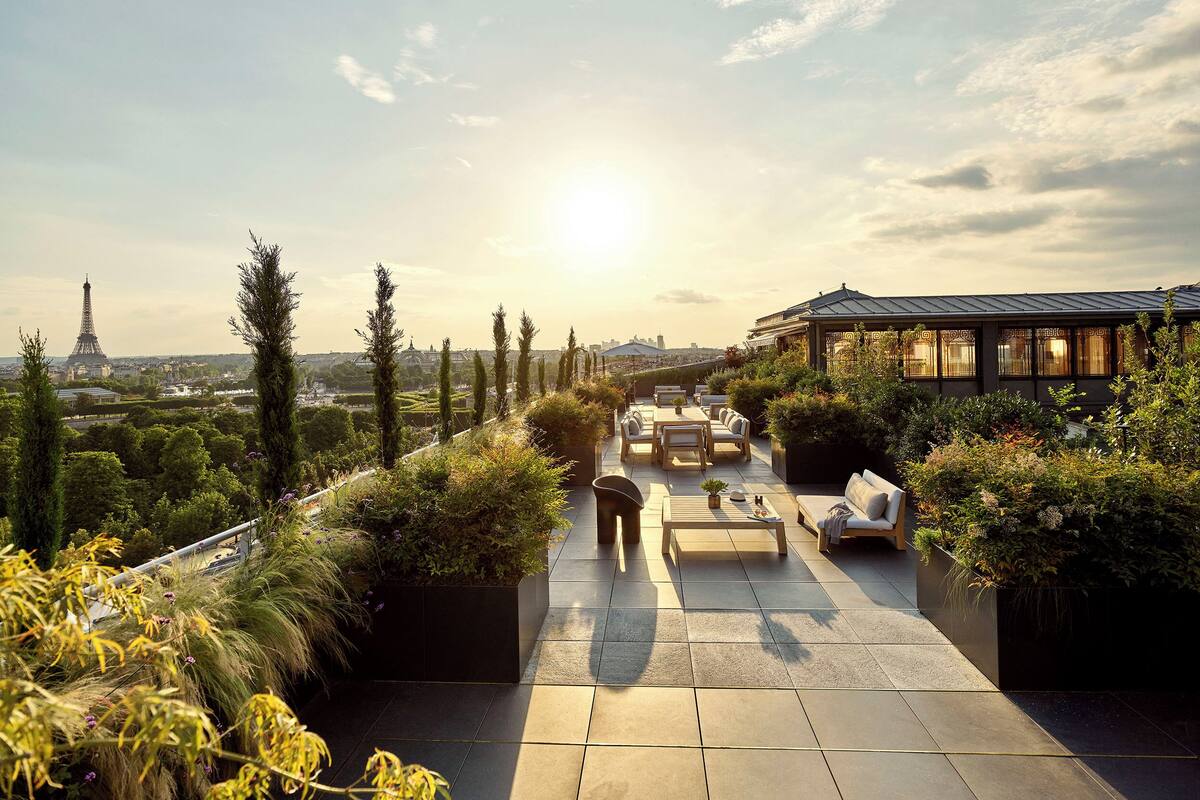 A rooftop terrace with outdoor seating, a view of the Eiffel Tower, and a garden area.