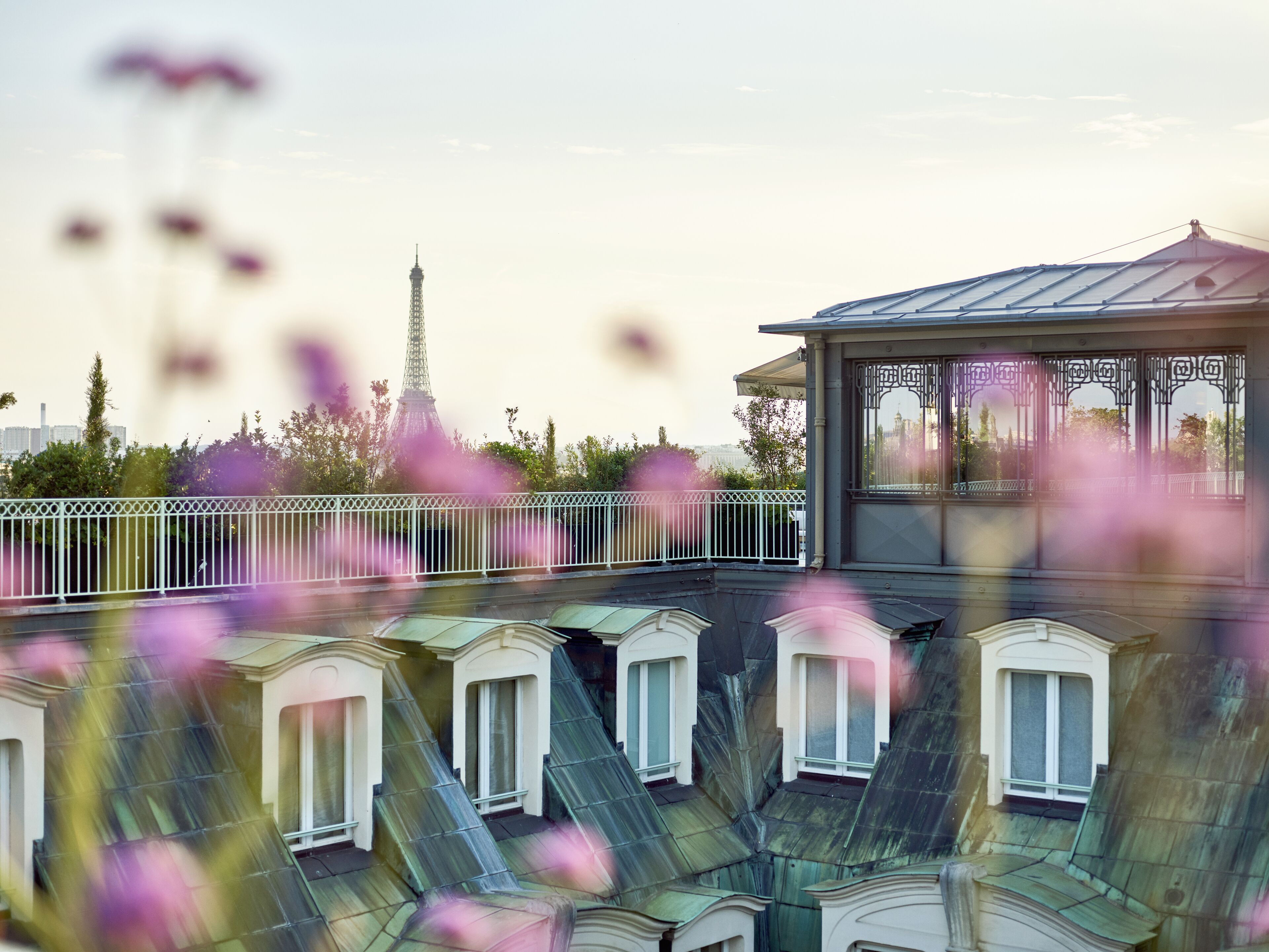 Une terrasse sur le toit offrant une vue sur la Tour Eiffel, avec un espace salon couvert et de nombreuses fenêtres.