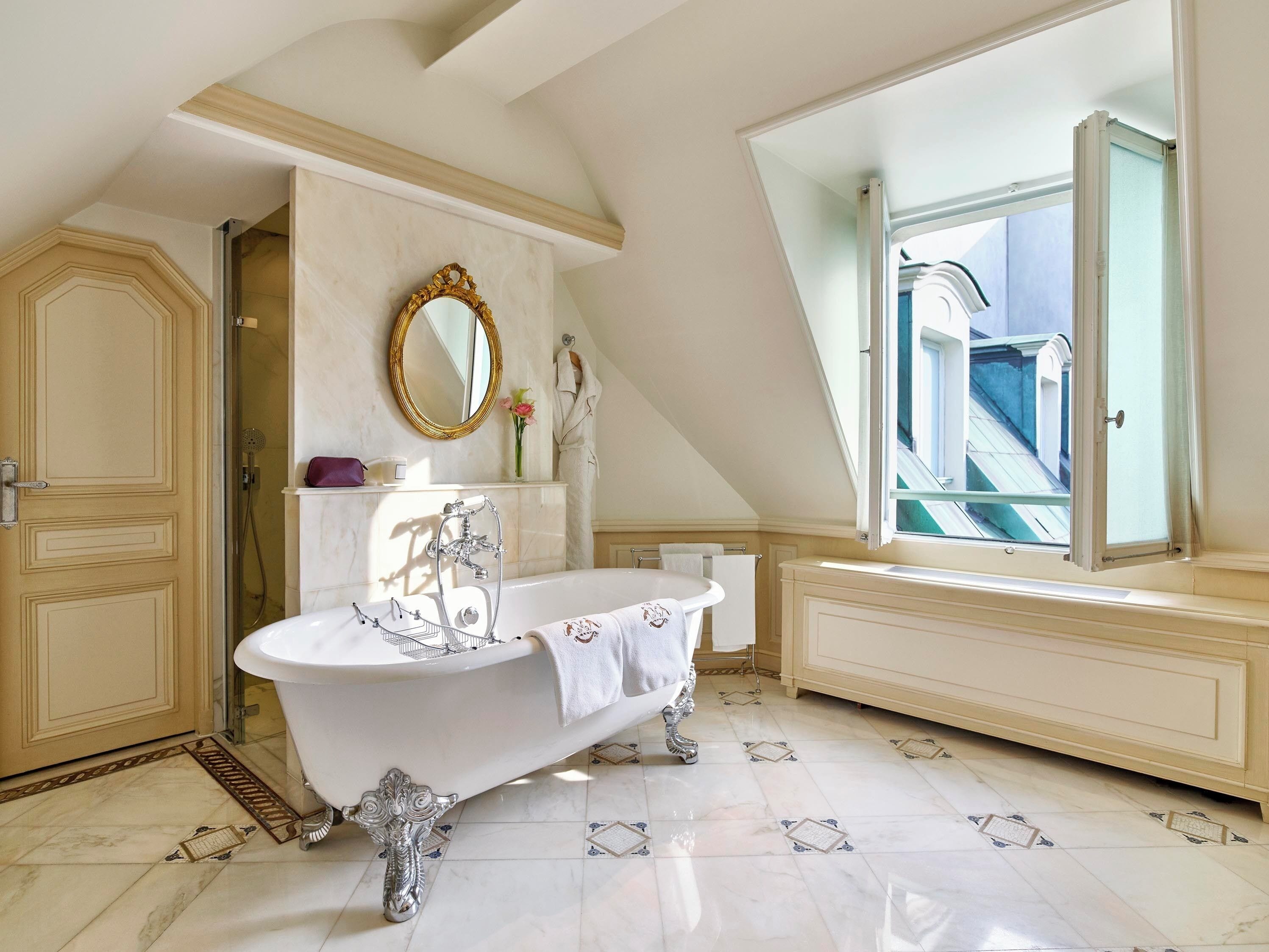 A bathroom with a freestanding bathtub, a large mirror, and a view of a balcony.