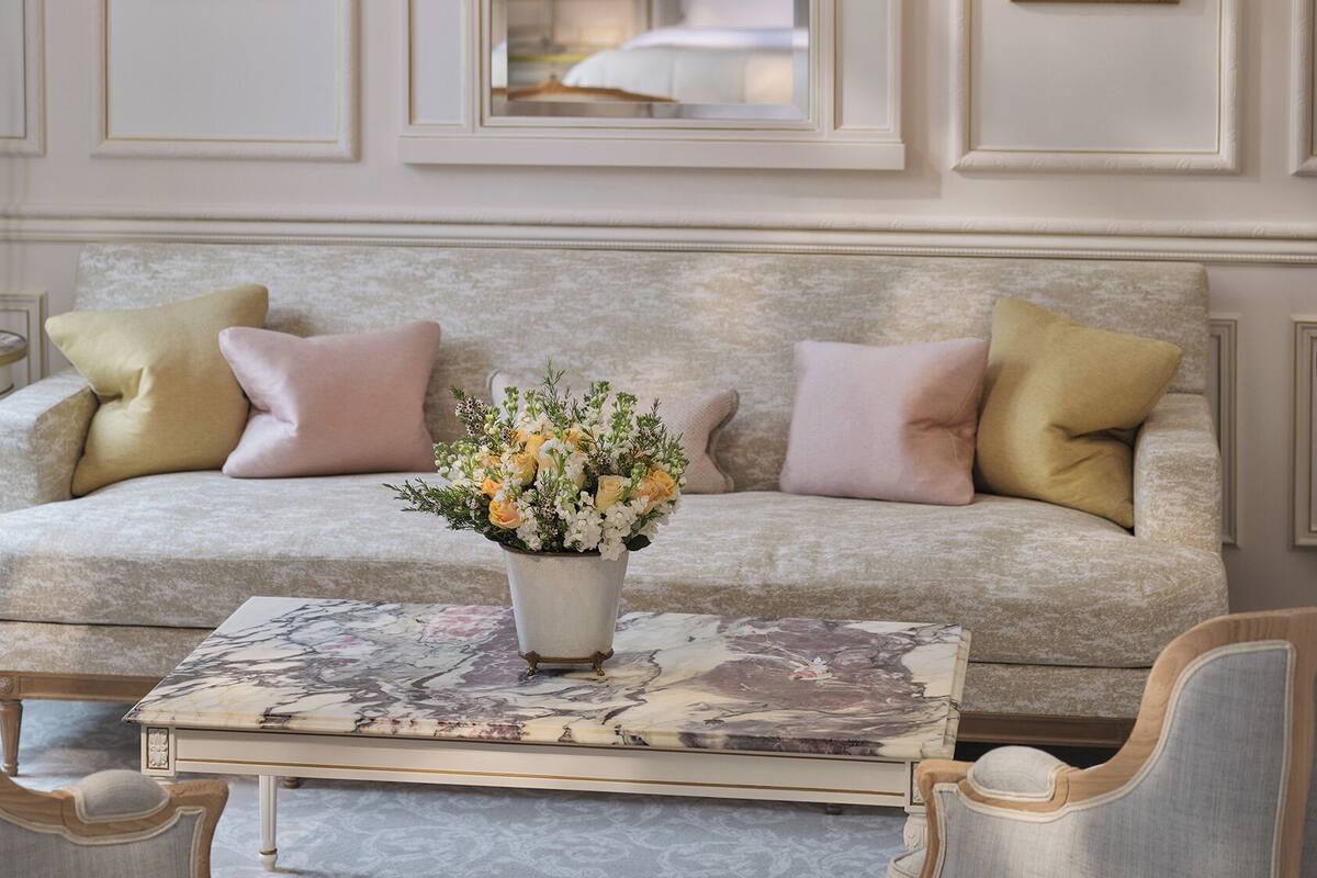 A room with a sofa, a coffee table with a floral arrangement, and two framed botanical prints on the wall.