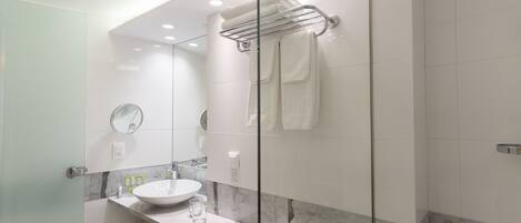 A modern bathroom with a glass shower enclosure, a white sink with a marble countertop, and a towel rack.