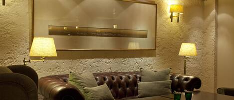 A cozy seating area with a leather couch, a table, and wall-mounted lamps.