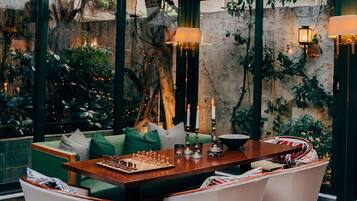 A cozy indoor setting with a wooden table, chessboard, and cushions.