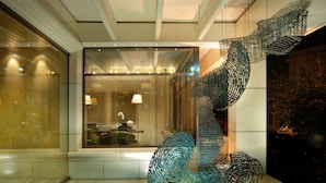 A modern interior with a spiral staircase made of metal, a reception area with a desk and chairs, and a glass wall with a view of the interior.
