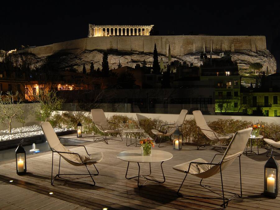 A rooftop terrace with lounge chairs, a table with a vase of flowers, and a view of a historic building.