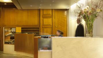 A reception area with wooden paneling, a marble counter, and a vase with flowers.