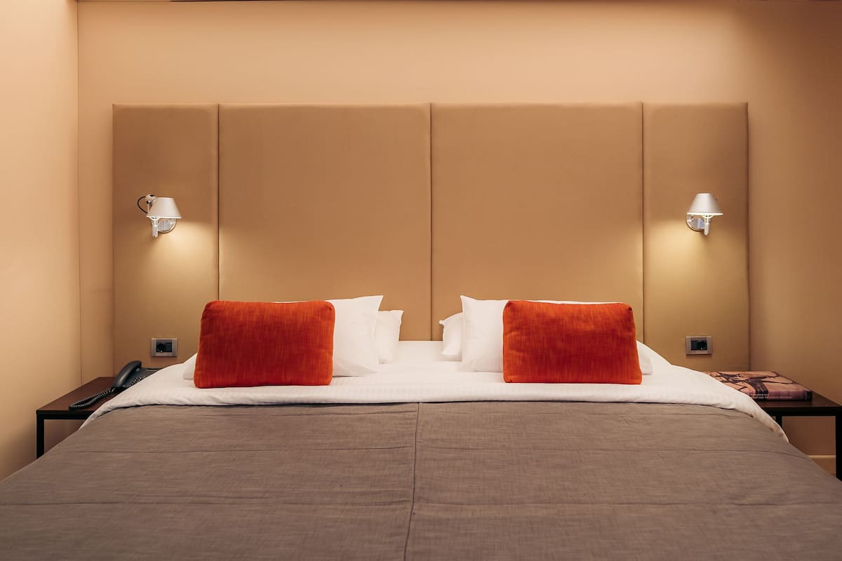 Une chambre d’hôtel avec un grand lit, deux lampes de chevet et un téléphone sur une table de chevet.