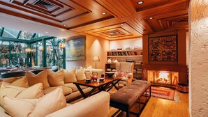 A cozy living room with a fireplace, wooden ceiling, and a bookshelf.