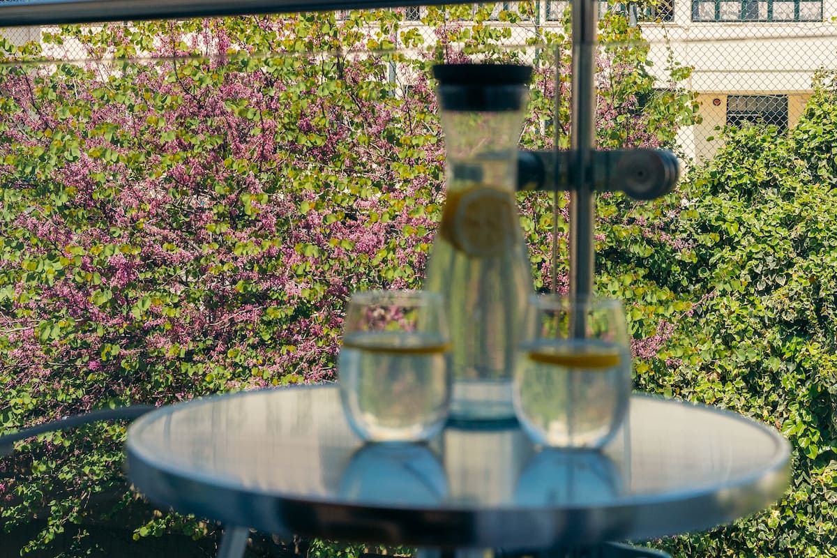 Un balcon avec un narguilé, une vue sur des ruines antiques et une clôture ornée de verdure.