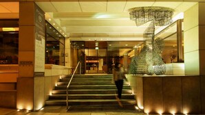 A hotel lobby with a staircase, a modern sculpture, and a sign advertising a stunning view and cool drinks.