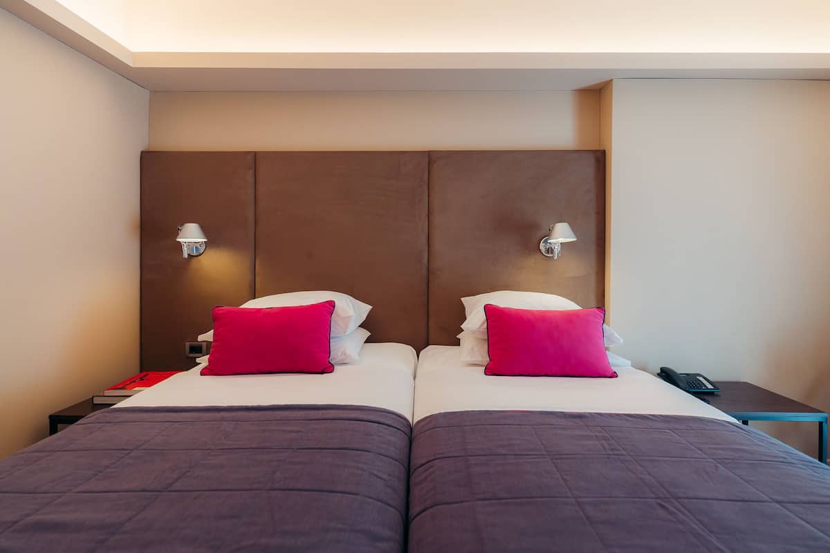 Un lit double avec une tête de lit, deux tables de chevet, une petite table et une lampe.