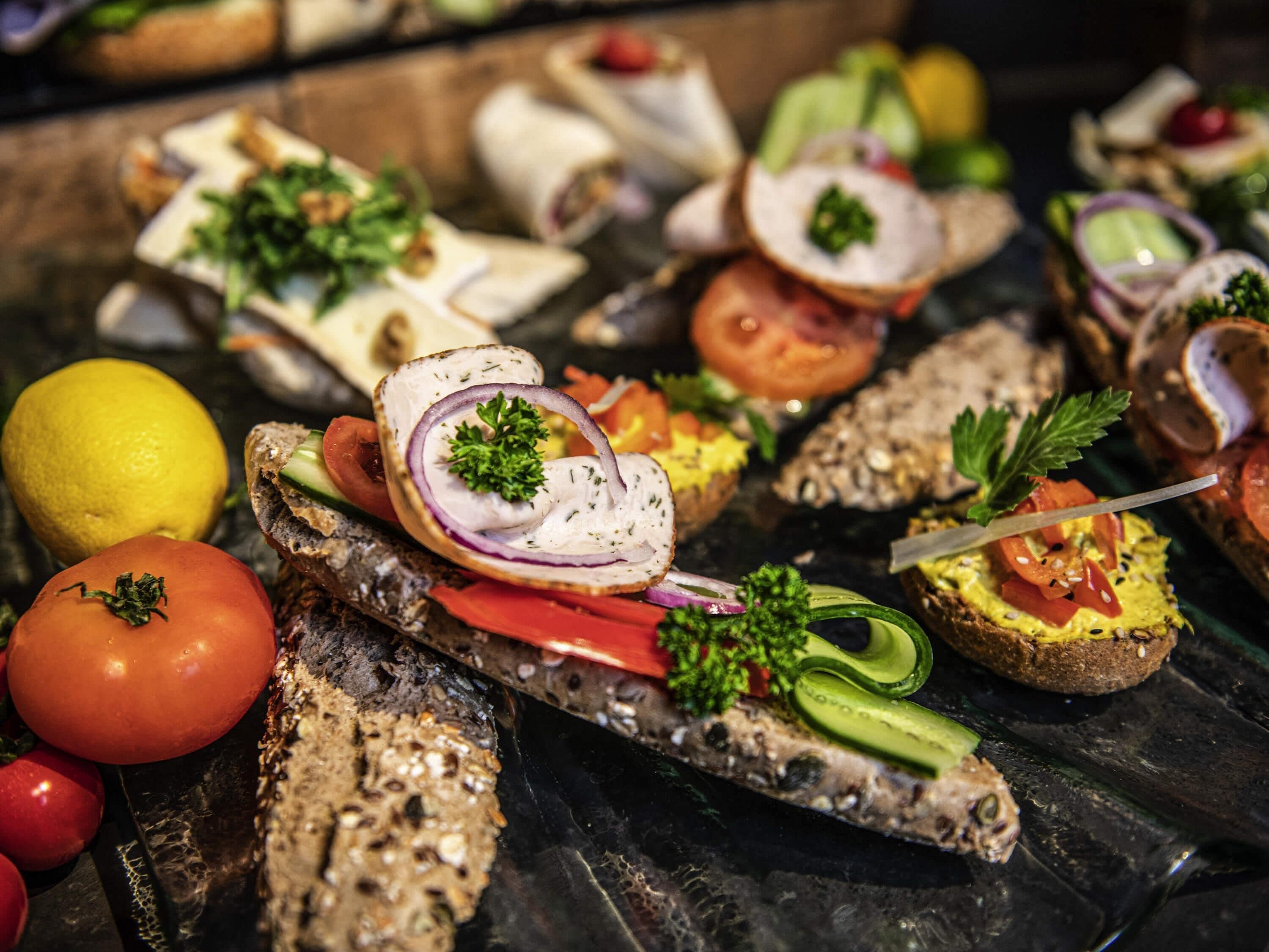 Una variedad de aperitivos en un plato, incluyendo pan con diferentes ingredientes y adornos.