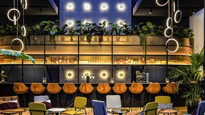 A modern lounge area with a variety of seating options, including sofas and chairs, and a bar area with a glass partition. - Mercure Antwerp City South (Antwerp)