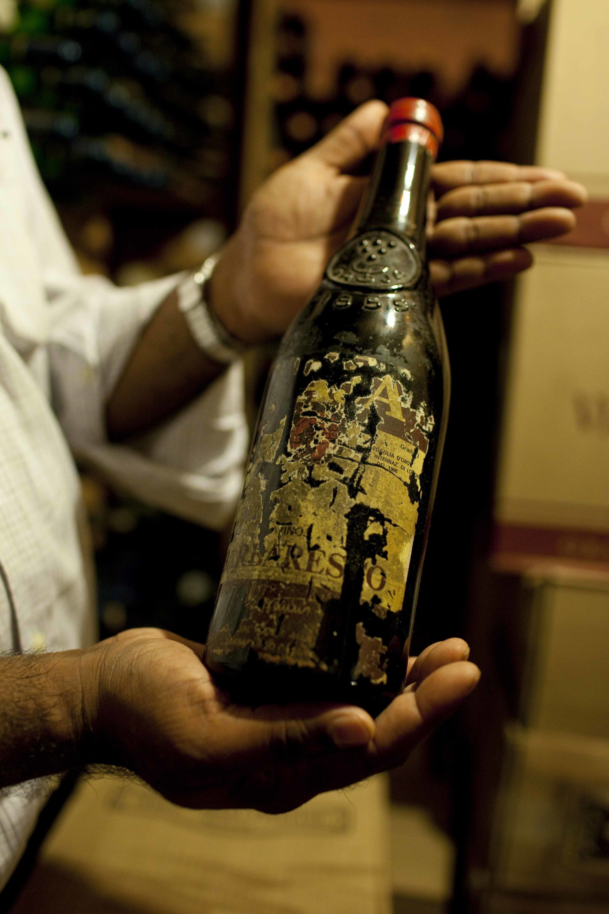 A person holding a bottle with a worn label.