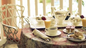 A table set for breakfast with tea, coffee, and pastries, overlooking a garden. - Graycliff Hotel And Restaurant (Nassau)
