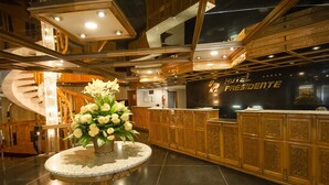Un vestíbulo con mostrador de recepción, una escalera y un elemento decorativo central.