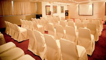 A conference room with rows of white-covered chairs and a carpeted floor.